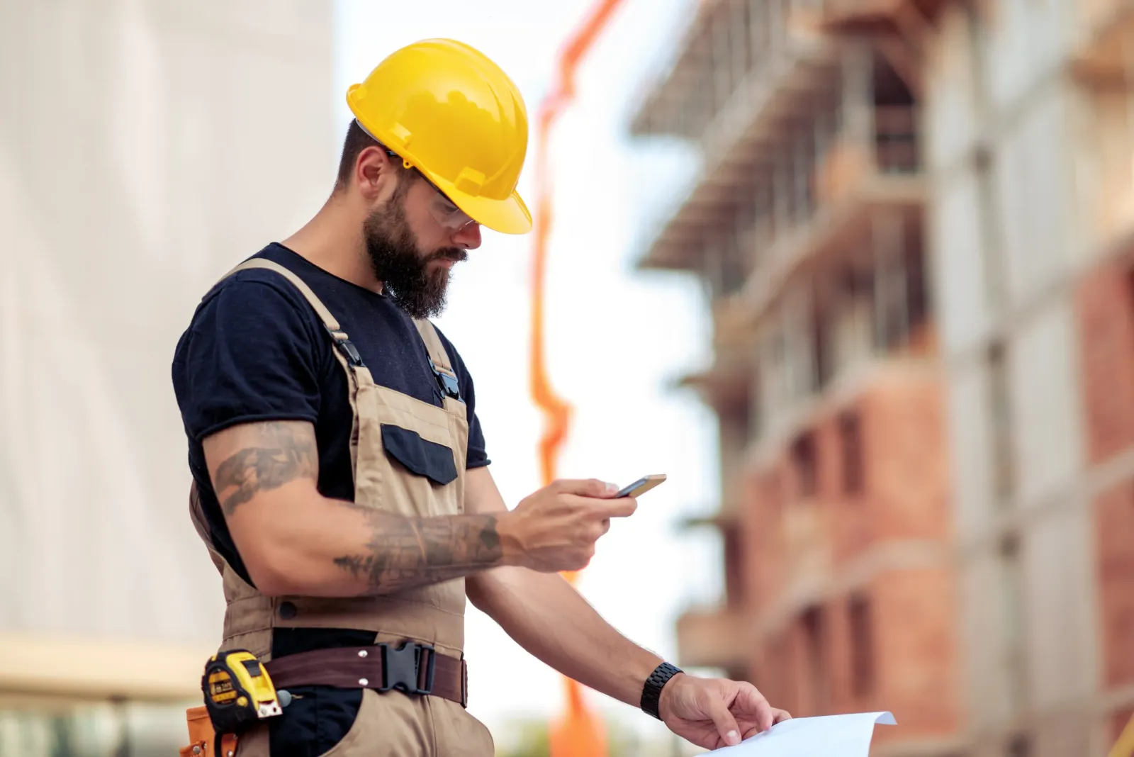 Contractor on job site using a construction management app on his phone.