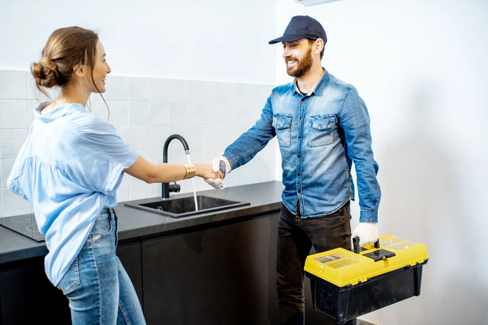 Contractor shaking hands with a client after completing a job in her kitchen.