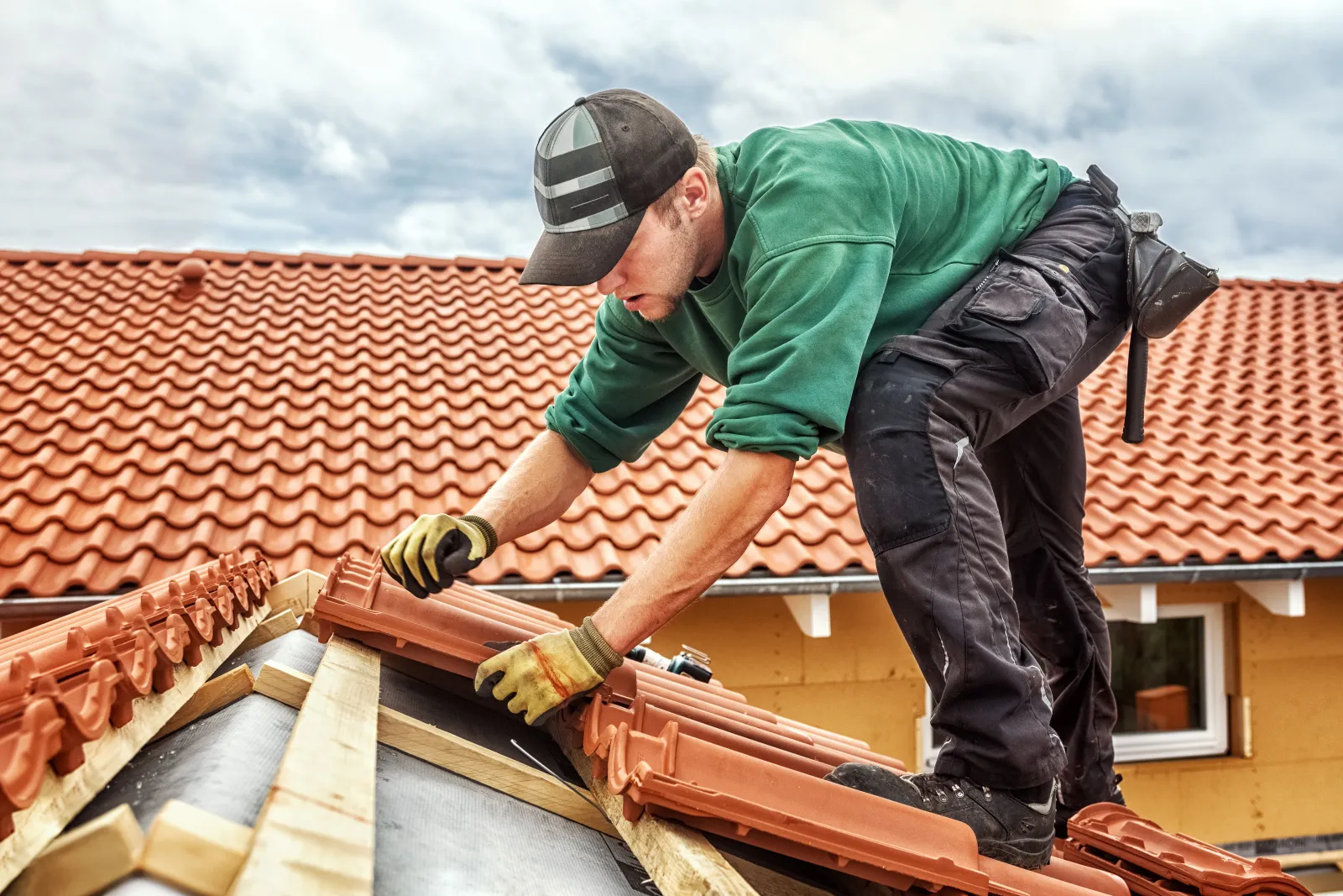 Roofer at work, installing clay roof tiles