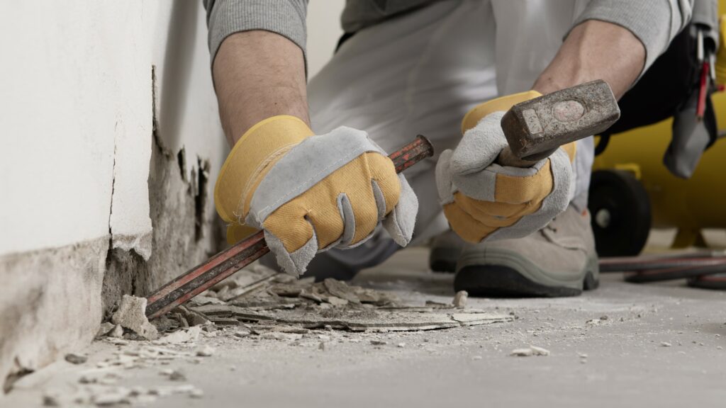 Contractor using a hammer and chisel on a job site.