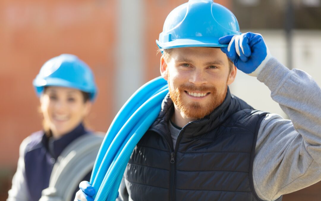 Two contractors on a job site smiling and looking at the viewer