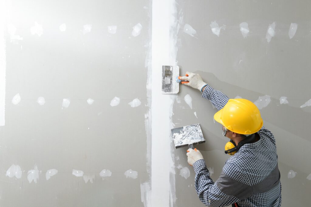 A contractor working on a wall.
