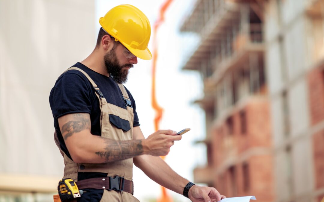 Contractor on job site using a construction management app on his phone.