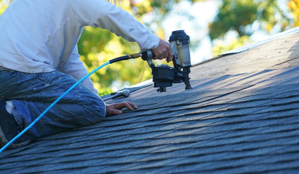 Contractor works on roof with nail gun.