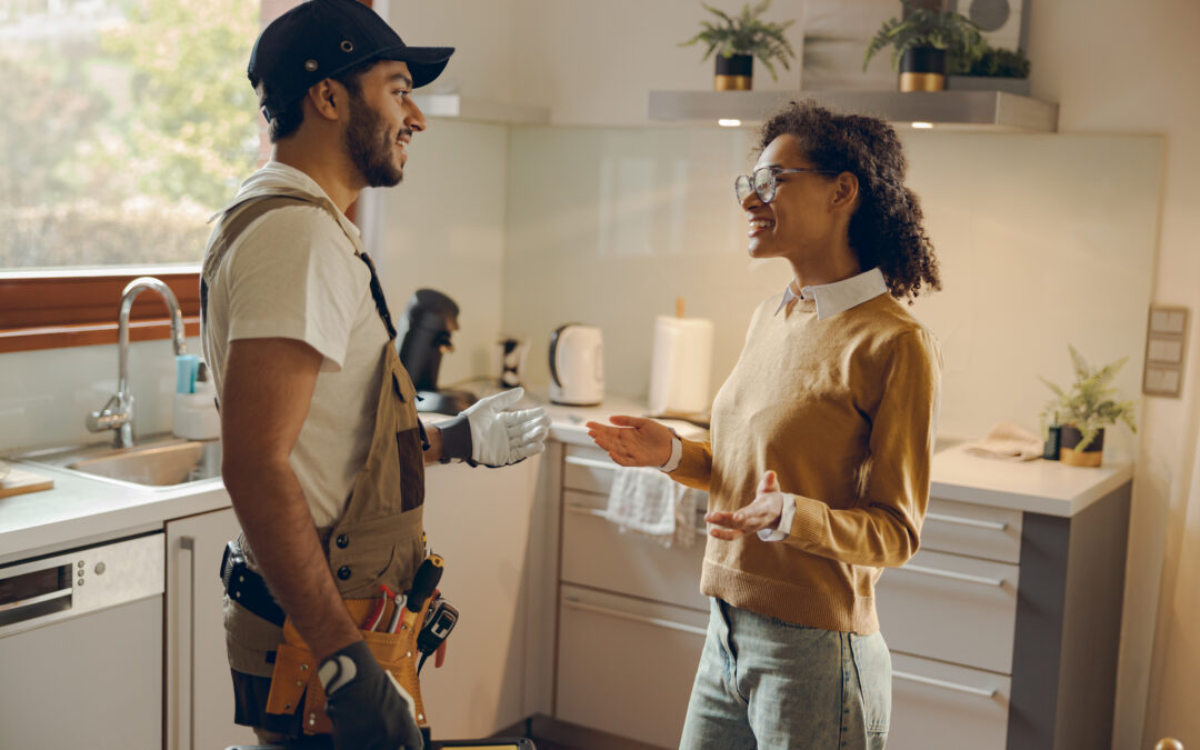 Handyman and happy client standing and discussing in a kitchen.