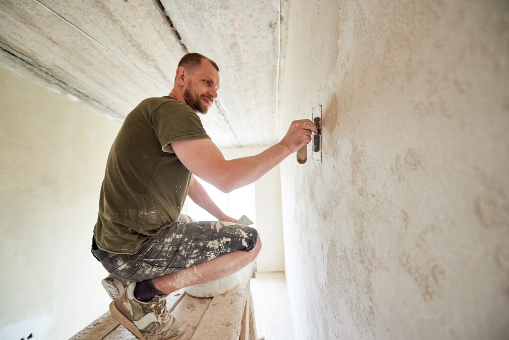 Contractor puttying the walls of a small room