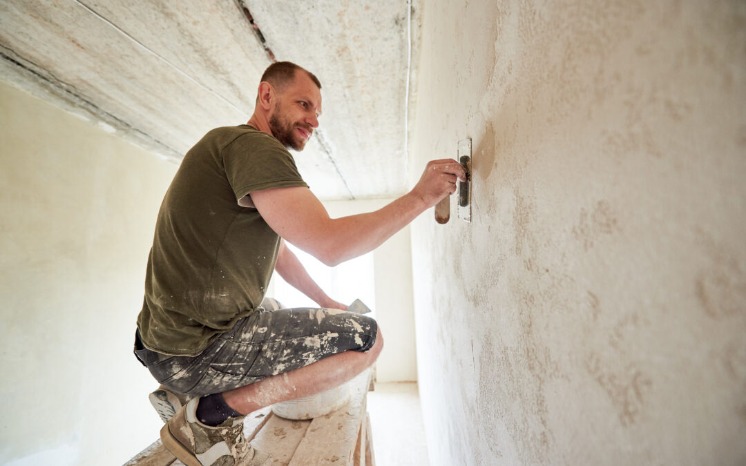 Contractor puttying the walls of a small room