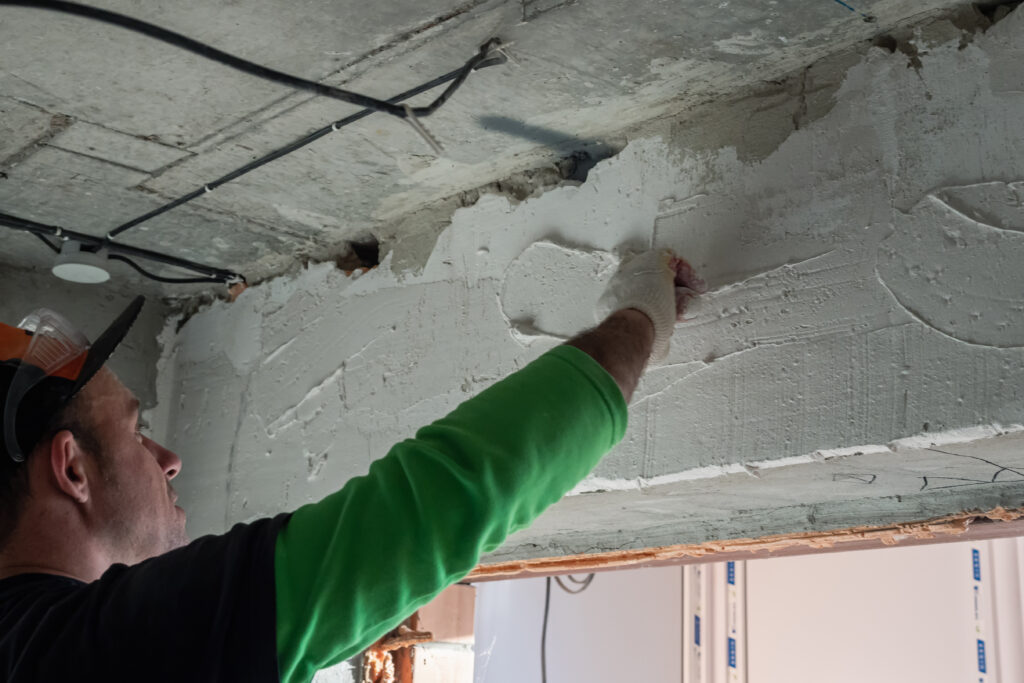 A construction worker plastering a wall with a small trowel